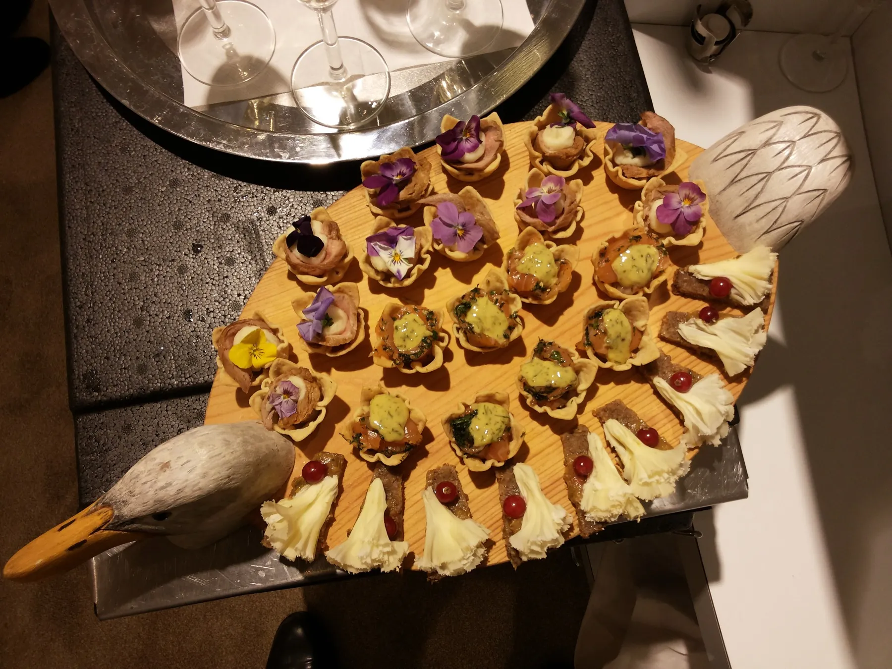 Wooden serving board with canapés and edible flowers
