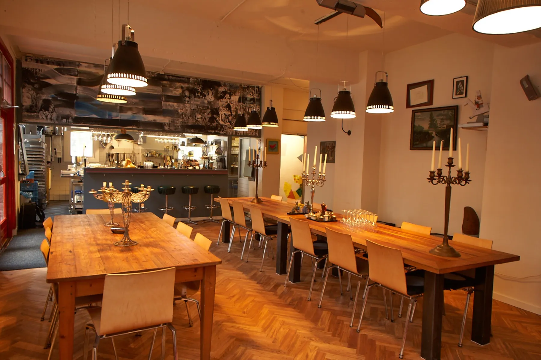 The cook’s studio: two long wooden tables, candlesticks and an open kitchen